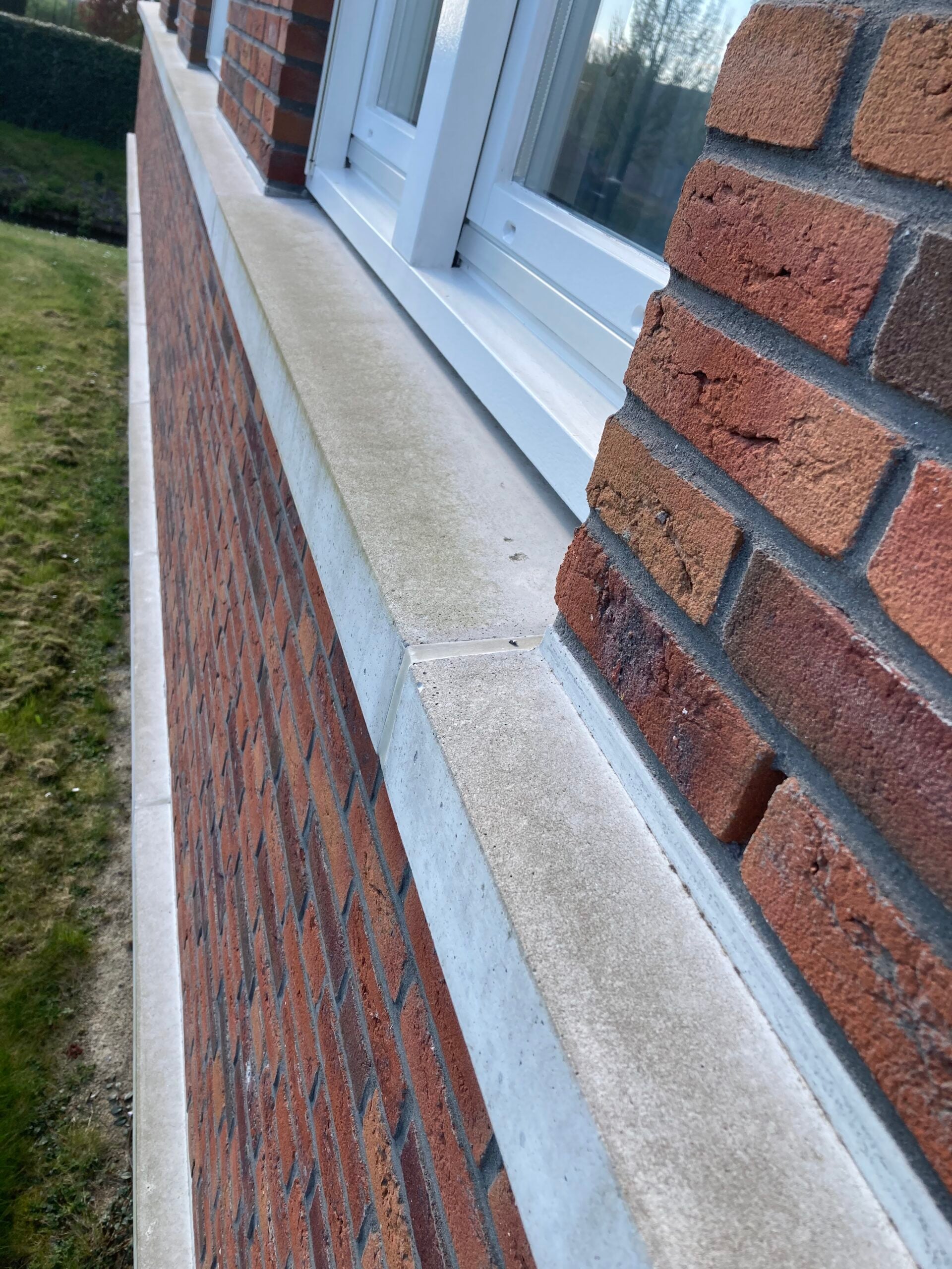 Betonnen latei onder een raam in een bakstenen gevel