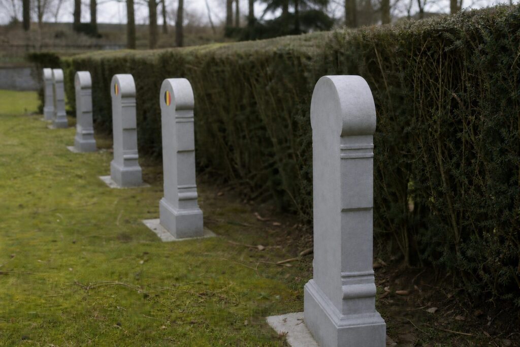 Atmospheric image of rows of Belgian military gravestones along a hedge at Champion War Cemetery