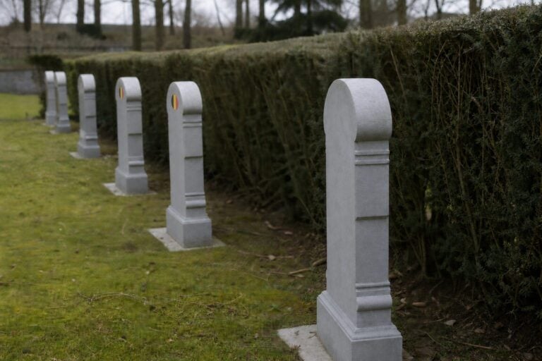 Stimmungsbild von Reihen belgischer Militärgrabsteine entlang einer Hecke auf dem Ehrenfriedhof Champion